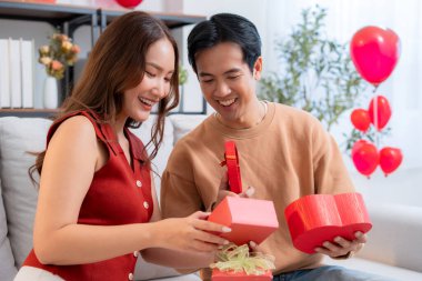 Romantik Asyalı çift, evde doğum günü ya da bayram kutlaması için kalp hediye kutusu veriyor ve alıyor. Sevgililer günü ya da tatilini aşkla kutluyor, romantik sevgililer günü festivali, heyecan hissediyorlar..