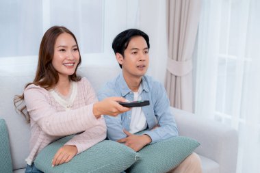 Mutlu Asyalı çift birlikte televizyon seyrediyor. Oturma odasındaki kanepede oturup uzaktan kumandayla film kanalını değiştiriyorlar. Bir çift medya eğlencesinin tadını çıkarıyor..