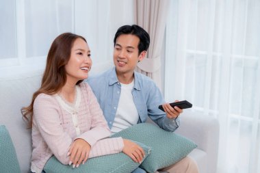 Mutlu Asyalı çift birlikte televizyon seyrediyor. Oturma odasındaki kanepede oturup uzaktan kumandayla film kanalını değiştiriyorlar. Bir çift medya eğlencesinin tadını çıkarıyor..