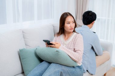 Mutsuz Asyalı çift ilişki sorunu yaşıyor, kadın üzgün görünüyor, erkek ise akıllı telefon, çatışma ve evdeki kanepe, sosyal medya bağımlılığı, stres ve gerilim için partnerini görmezden geliyor..