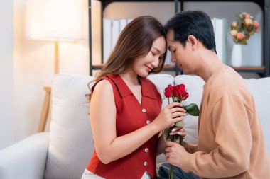 Sevgililer Günü 'nü ya da yıldönümünü evde kutlayan Asyalı mutlu bir kadın. Neşeli sürpriz hediyeye aşık genç bir çift. Romantik tatil..