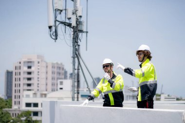 Profesyonel telekomünikasyon teknisyeni konuşuyor telsiz telsiz kumandası çatı baz istasyonu mühendisi verici sinyal ağı kablosuz teknoloji servisini inceliyor..