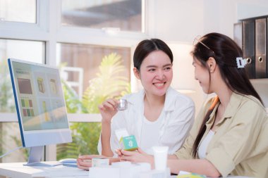 Kozmetik ambalaj tasarımı geliştirme için yapay zeka asistanı kullanan iki Asyalı kadın tasarımcı, yaratıcı takım işi pazarlama, fikir için yapay zeka ile ürün tasarımı projesi.