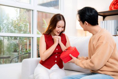 Mutlu Asyalı adam Sevgililer Günü 'nü ya da yıldönümünü evde kutlayan sevgilisine kalp hediye kutusu veriyor. Mutlu sürpriz hediyeye aşık genç bir çift, ilişki ve kaynaşma..