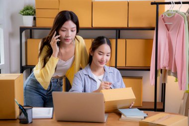 İç işlerinde iki Asyalı kadın e-ticaret girişimi, iki genç girişimci yönetim emri, çevrimiçi satıcı takım çalışması, hazırlık dağıtımı için ürün paketleme, perakende ve nakliye, iş konsepti.