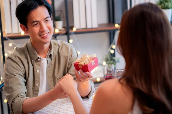 Romantik Asyalı erkek sevgilisine hediye paketi veriyor. Sevgililer günü için sürpriz ya da restoranda yıldönümü yemeği. Mutlu çift, aşkı hediyeyle, mutlulukla ve ilişkiyle kutluyor..