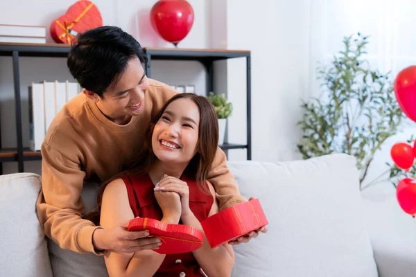 Mutlu Asyalı adam Sevgililer Günü 'nü ya da yıldönümünü evde kutlayan sevgilisine kalp hediye kutusu veriyor. Mutlu sürpriz hediyeye aşık genç bir çift, ilişki ve kaynaşma..
