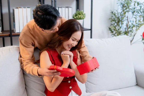 Mutlu Asyalı adam Sevgililer Günü 'nü ya da yıldönümünü evde kutlayan sevgilisine kalp hediye kutusu veriyor. Mutlu sürpriz hediyeye aşık genç bir çift, ilişki ve kaynaşma..