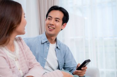 Mutlu Asyalı çift birlikte televizyon seyrediyor. Oturma odasındaki kanepede oturup uzaktan kumandayla film kanalını değiştiriyorlar. Bir çift medya eğlencesinin tadını çıkarıyor..