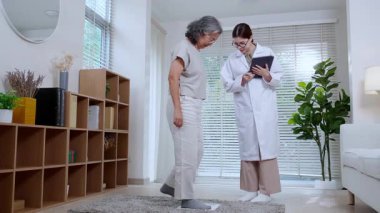 Asyalı kadın doktor, tıbbi sağlık konusunda uzman, beslenme uzmanı, yaşlılarla tartılırken, klinikteki veri kaydı, danışma ve teşhis için tablet kullanılıyor..