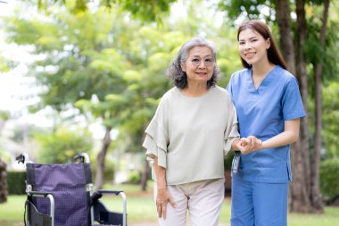Asyalı kadın bakıcı kıdemli hastaya fiziksel rehabilitasyon için yardım ediyor, profesyonel hemşire parkta yaşlı kadını destekliyor, terapi için iyileşme ve hareket kabiliyeti, sağlık hizmetleri.