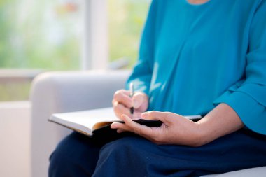 Kapalı kapılar ardında kitap yazan son sınıf öğrencisi kadın evde rahat bir şekilde oturuyor. Yaşlı kadın, hafta sonu rahat, hobi ve eğlence dolu günlükler yazıyor. Yaşam tarzları konsepti..