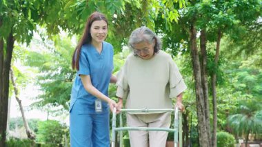 Asyalı kadın bakıcı, Walker 'a fiziksel rehabilitasyon ve terapi için yardım ediyor, hemşire, parkta yürüyen yaşlı kadına bakıyor, sağlık ve sağlıklı emeklilik, tıbbi konsept.