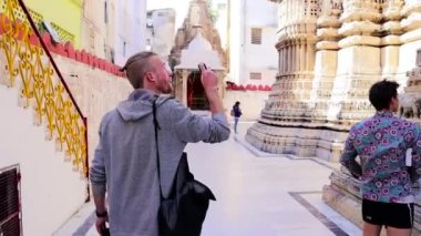 Udaipur, Rajasthan Hindistan - 02 02 02 2020: Beyaz adam tapınak oymalarını kamerasıyla yakalıyor. Rajasthan Turizmi.