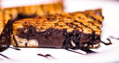 Sandviçler üçgen şeklinde kesiliyor ve beyaz bir tabakta düzenleniyor. Tabak bir masaya konur.