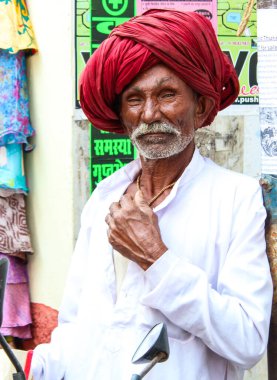Pushkar, Rajasthan, Hindistan - 22 Aralık 2014: Sarı kostüm giymiş bir kadın elinde kase tutuyordu. Kadınlar altın bir başlık takıyor ve siyah bir peruğu var. Ayrıca çiçek çelengi takıyor..