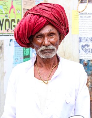 Pushkar, Rajasthan, Hindistan - 22 Aralık 2014: Sarı kostüm giymiş bir kadın elinde kase tutuyordu. Kadınlar altın bir başlık takıyor ve siyah bir peruğu var. Ayrıca çiçek çelengi takıyor..