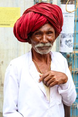 Pushkar, Rajasthan, Hindistan - 22 Aralık 2014: Sarı kostüm giymiş bir kadın elinde kase tutuyordu. Kadınlar altın bir başlık takıyor ve siyah bir peruğu var. Ayrıca çiçek çelengi takıyor..