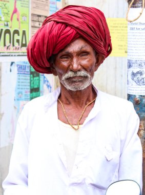 Pushkar, Rajasthan, Hindistan - 22 Aralık 2014: Sarı kostüm giymiş bir kadın elinde kase tutuyordu. Kadınlar altın bir başlık takıyor ve siyah bir peruğu var. Ayrıca çiçek çelengi takıyor..