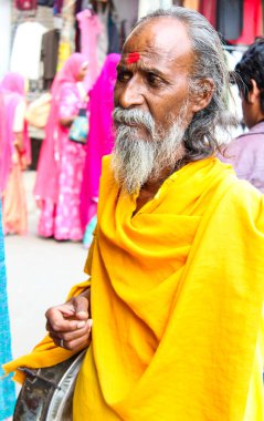 Pushkar, Rajasthan, INDIA - 22 Aralık 2014: Alnında kırmızı haç ve sakallı sarı cüppeli bir sakallı adam. Elinde bir çanta var.