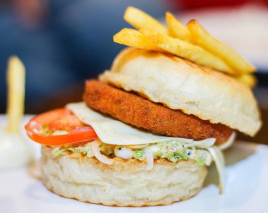 Hamburger, çörek ve bir parça peynir. Hamburgerin üzerinde de bir parça marul var.