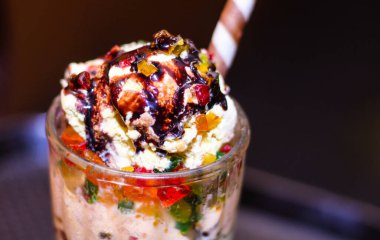 Bardakta lezzetli bir tatlı, üstüne de çikolata sosu. Dondurma kremalı, beyaz renkli ve sos koyu, koyu kahverengi.