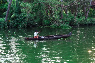 Alappuzha ya da Alleppey, Kerala, INDIA - 09 Şubat 2016: Bir adam gölde bir teknede oturuyor. Tekne küçük ve içinde bir adam var. Alappuzha (Alleppey). Kerala Turizmi