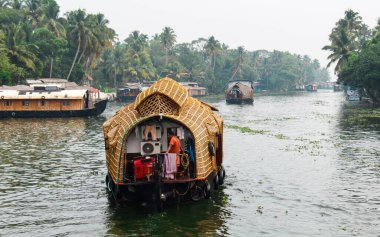 Alappuzha ya da Alleppey, Kerala, INDIA - 09 Şubat 2016: Suda üzerinde bir adam olan bir tekne yüzüyor. Teknedeki adam güvertede duruyor, denize bakıyor. Alappuzha (Alleppey)