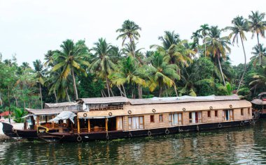 Alappuzha ya da Alleppey, Kerala, INDIA - FEBURY 09, 2016: Suda birçok kulübesi olan büyük bir tekne yüzüyor. Tekne palmiye ağaçları ile çevrilidir. Alappuzha (Alleppey). Kerala