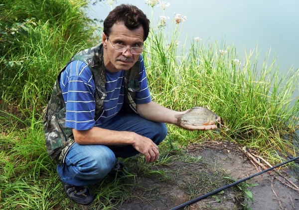 Fisherman with crucian on river Chagan — Stock Image Fisherman with crucian on river Chagan Stock Photo