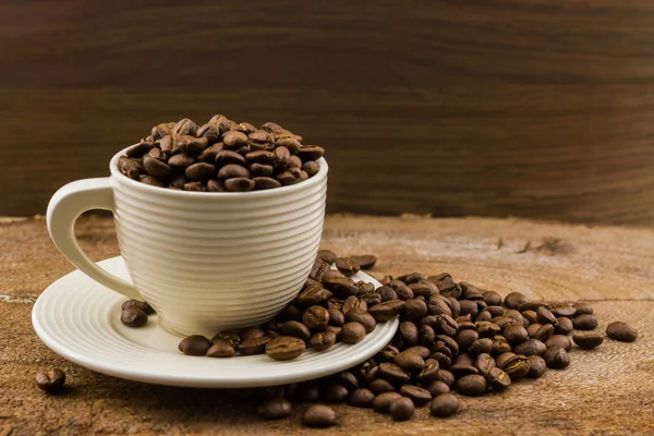 Graines de café torréfiées brunes dans une tasse de café . — Photo