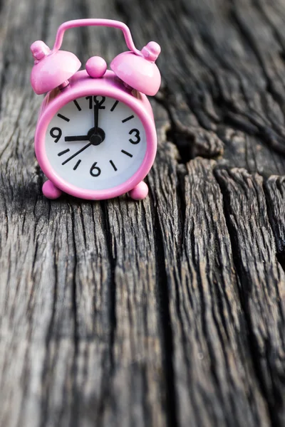 Pequeno relógio rosa sobre fundo de madeira . — Fotografia de Stock