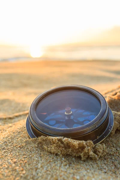 Antigua brújula en la arena al amanecer de la playa . — Foto de Stock
