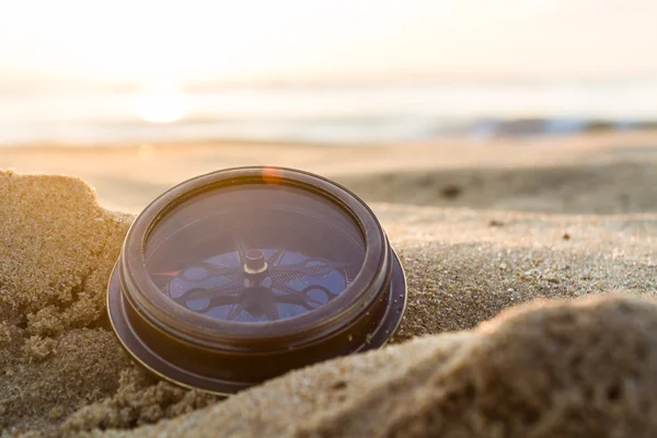 Oude kompas op het zand op het strand-Sunrise. — Stockfoto