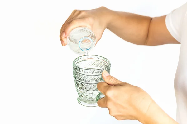 Female hand pouring water into a glass from bottle. — Stock Photo, Image