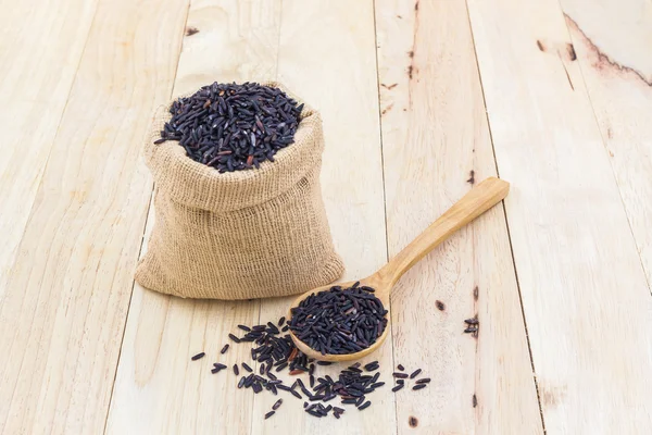 Arroz de bayas en una cuchara de madera y pequeño saco de arpillera . — Foto de Stock