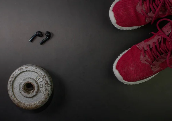 fitness background with red tennis shoes, weight plates and headphones