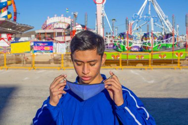 Panayırın önündeki İspanyol genç adam yüz maskesi takıyor. Latin gençliği