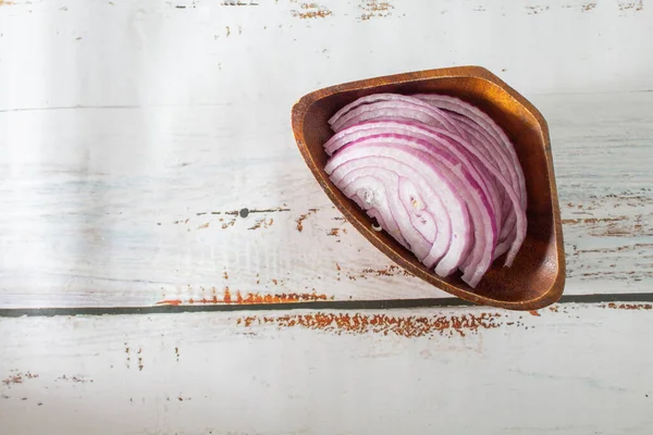 red onion cut into slices in wooden bowl on boards