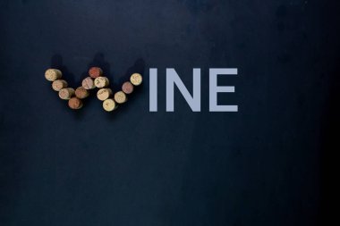 Şarap şişesi mantarları siyah arka planda şarap sözcüğünü tamamlıyor.