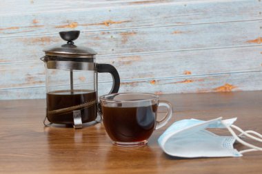 Yeni normal ve Fransız presi için maskenin yanında şeffaf bir fincan espresso.