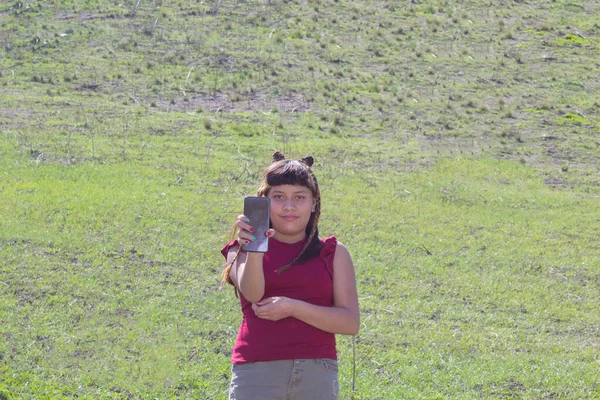 メキシコ人の少女が山の中で携帯電話を見せている — ストック写真