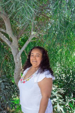 Parktaki ağacın önünde gülümseyen şişman Meksikalı kadın. Yerli