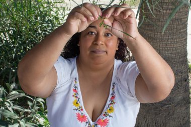 Meksikalı kadın bir ağacın altındaki parkta bahçıvanlık yapıyor. İspanyol.