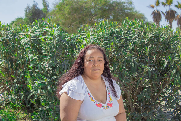 Мексиканская модель кудрявых волос, улыбающаяся в парке. hispanic