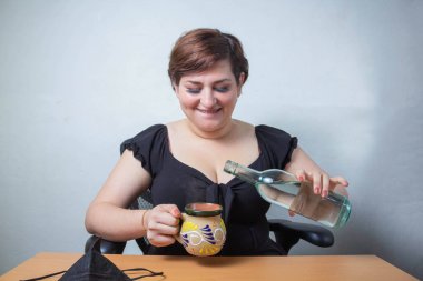 Kadın kahve bardağına alkol dolduruyor, votka, tekila ya da mezcal gibi.