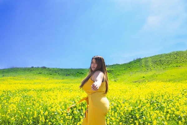 黄色の花でいっぱいの畑で夕日をポーズする美しい脂肪モデル — ストック写真
