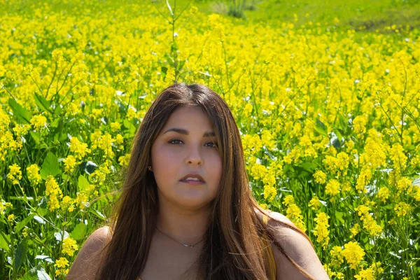 美しいヒスパニック系の女性は黄色の花のフィールドに座っている ぽっちゃりモデル — ストック写真