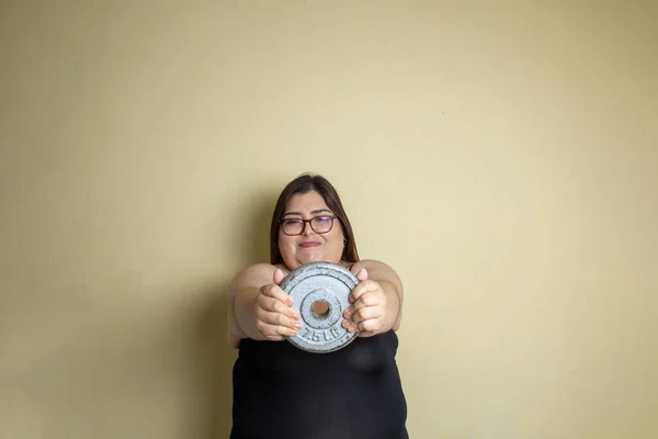fat woman exercising with dumbbell disc to lose weight and lead healthy life