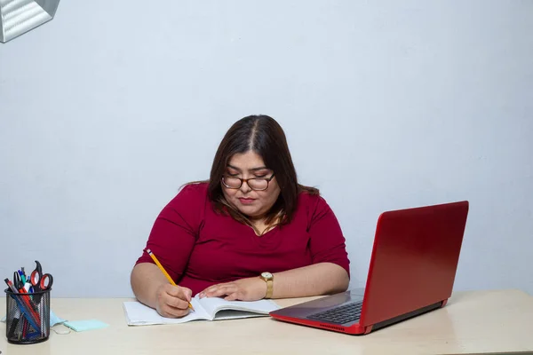 Obese woman typing her new diet from an online page on laptop from home office. fat model